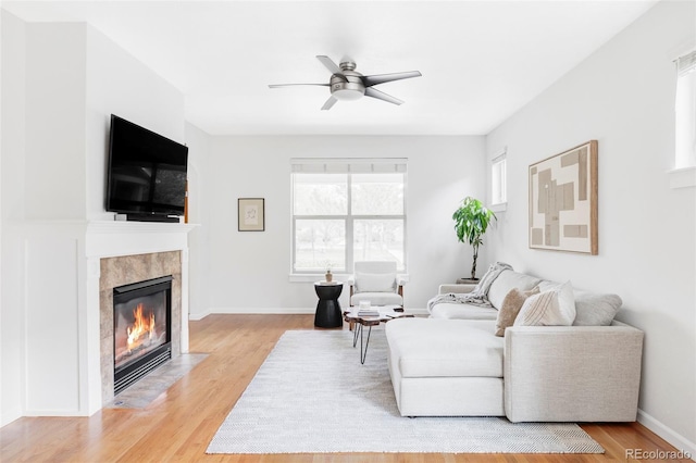 living area featuring a ceiling fan, plenty of natural light, light wood finished floors, and a fireplace