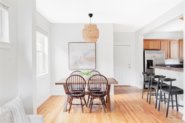 dining space featuring baseboards and light wood-style flooring