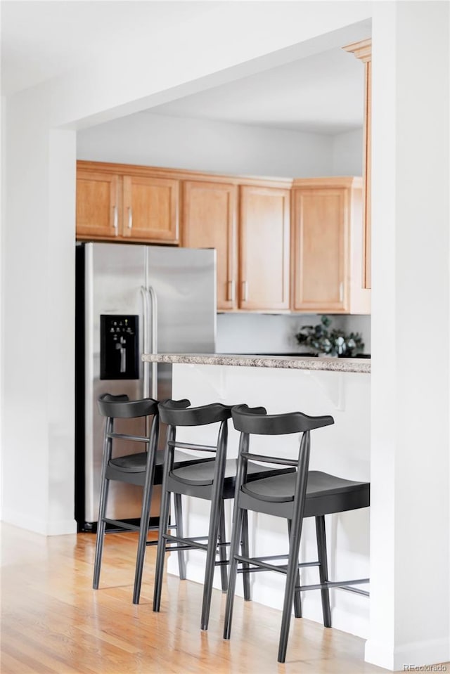 kitchen featuring light wood-style flooring, light brown cabinets, and a kitchen bar