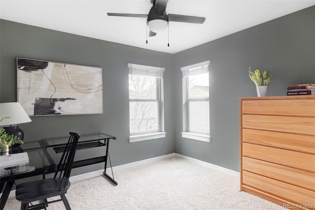 carpeted home office with baseboards and a ceiling fan