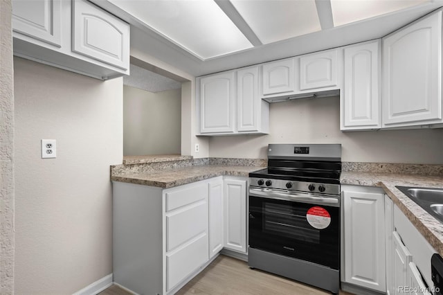 kitchen with light wood-style floors, light countertops, stainless steel electric range, and white cabinets