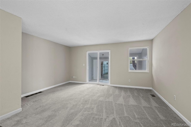 empty room with a textured ceiling, visible vents, baseboards, and carpet
