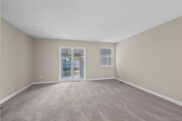 unfurnished room featuring baseboards, carpet, a textured ceiling, and visible vents