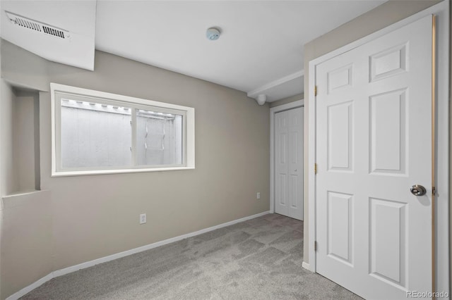 unfurnished bedroom featuring carpet floors, baseboards, a closet, and visible vents