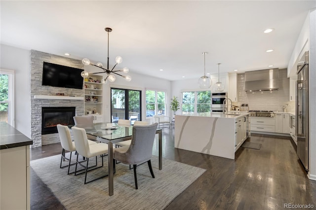 11389 E Maplewood Ave, Englewood, CO 80111 - dining space with a stone fireplace, dark wood-style flooring, recessed lighting, and a chandelier