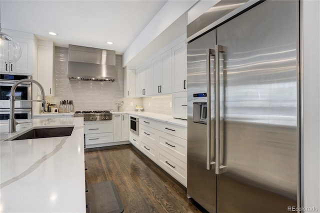 11389 E Maplewood Ave, Englewood, CO 80111 - kitchen featuring appliances with stainless steel finishes, wall chimney exhaust hood, light stone counters, dark wood finished floors, and recessed lighting
