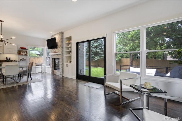 11389 E Maplewood Ave, Englewood, CO 80111 - living room with a stone fireplace, built in shelves, dark wood-type flooring, and a chandelier
