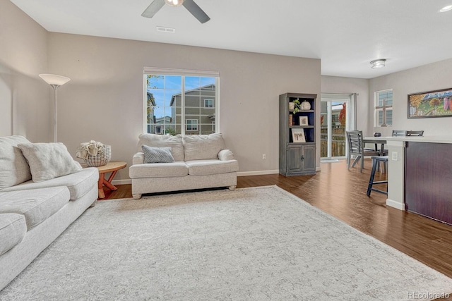 living room with a wealth of natural light, dark hardwood / wood-style floors, and ceiling fan