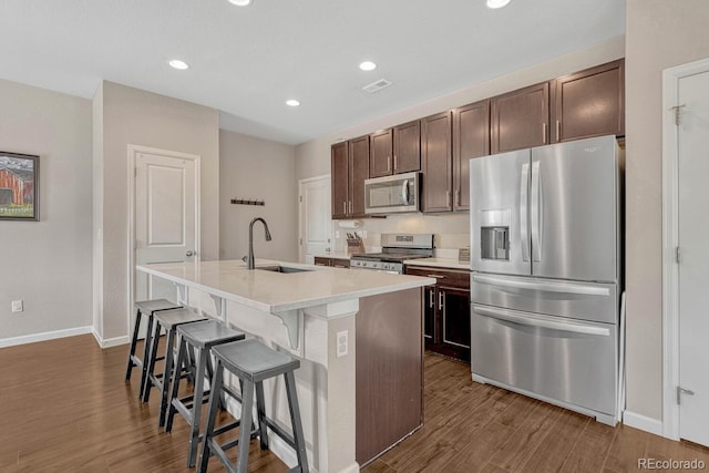 kitchen featuring sink, a breakfast bar area, a kitchen island with sink, dark brown cabinets, and appliances with stainless steel finishes