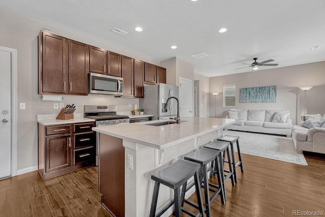 kitchen featuring sink, stainless steel appliances, dark hardwood / wood-style floors, a kitchen island with sink, and a breakfast bar