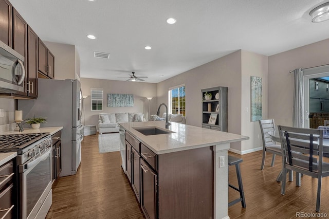 kitchen with a center island with sink, sink, a breakfast bar area, dark brown cabinetry, and stainless steel appliances