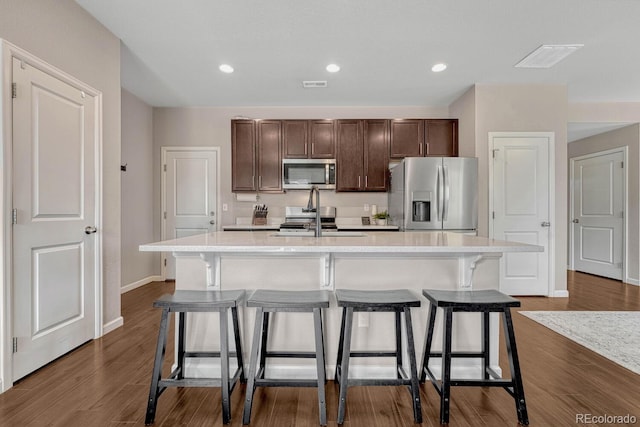 kitchen with a kitchen breakfast bar, sink, stainless steel appliances, and an island with sink