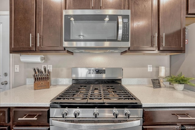 kitchen featuring dark brown cabinetry, light stone counters, and appliances with stainless steel finishes