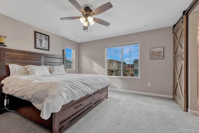 bedroom with light carpet, a barn door, and ceiling fan