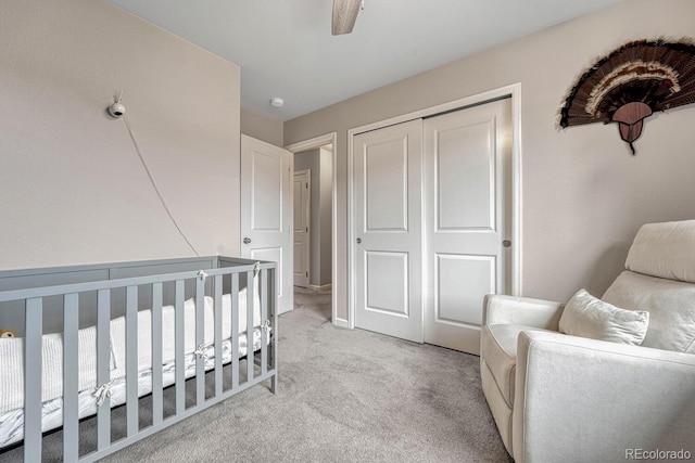 carpeted bedroom featuring ceiling fan, a closet, and a nursery area