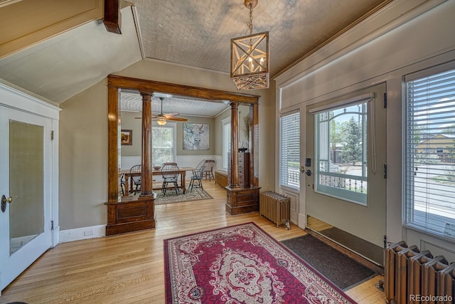 403 Scott St, Salida, CO 81201 - foyer entrance with radiator heating unit, light wood-style flooring, vaulted ceiling, a chandelier, and decorative columns