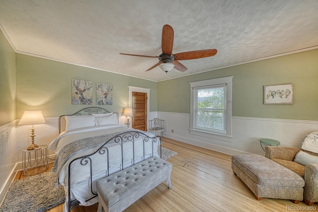 403 Scott St, Salida, CO 81201 - bedroom with light wood finished floors, a wainscoted wall, a textured ceiling, a ceiling fan, and ornamental molding
