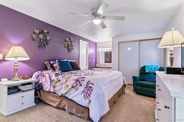 carpeted bedroom featuring a closet, ensuite bathroom, and ceiling fan