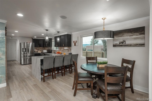 dining area with ornamental molding, sink, and light hardwood / wood-style floors