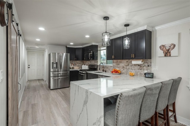 kitchen featuring light stone countertops, a breakfast bar, stainless steel appliances, kitchen peninsula, and a barn door