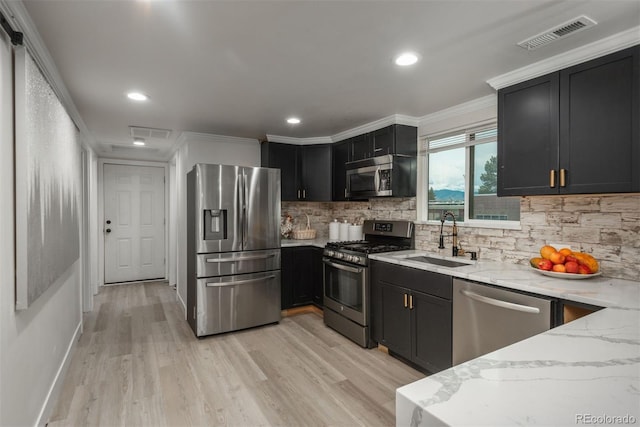 kitchen featuring light stone countertops, backsplash, crown molding, stainless steel appliances, and sink