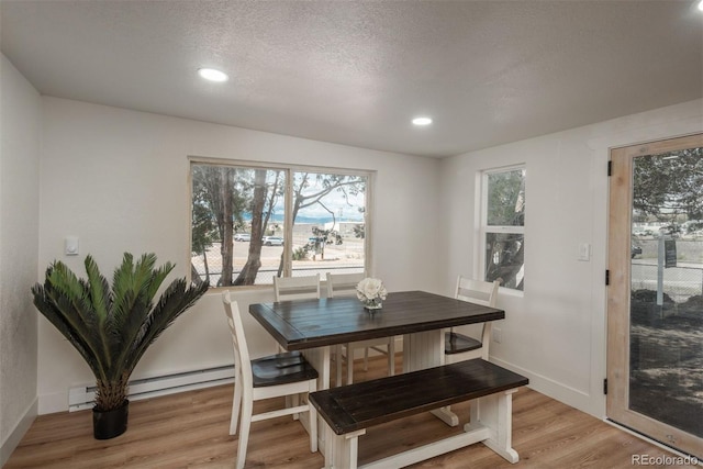 dining space with a textured ceiling, a baseboard radiator, and light hardwood / wood-style floors