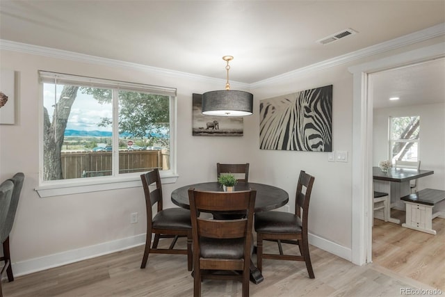 dining room with light wood-type flooring and ornamental molding