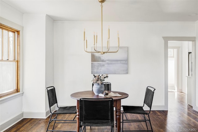 dining room featuring ornamental molding, dark wood-type flooring, and an inviting chandelier