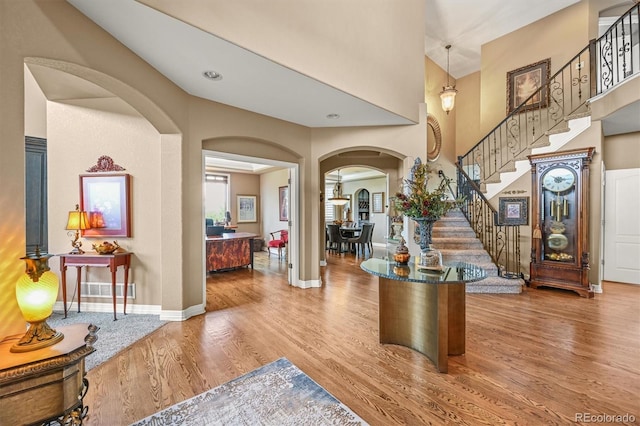 8518 High Rdg, Castle Pines, CO 80108 - entrance foyer with arched walkways, wood finished floors, stairs, a high ceiling, and baseboards