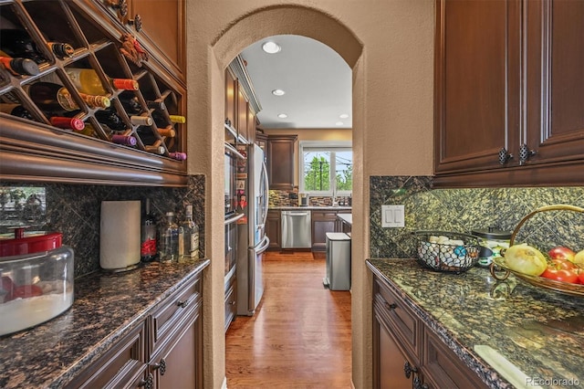8518 High Rdg, Castle Pines, CO 80108 - kitchen with appliances with stainless steel finishes, tasteful backsplash, arched walkways, light wood-style floors, and recessed lighting
