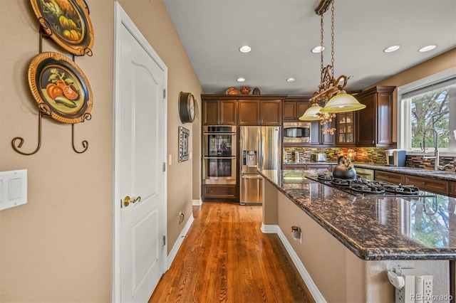 8518 High Rdg, Castle Pines, CO 80108 - kitchen with stainless steel appliances, wood finished floors, recessed lighting, glass insert cabinets, and backsplash