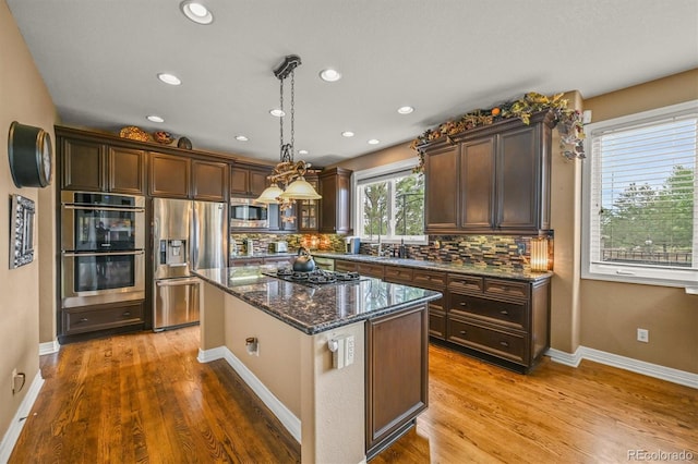 8518 High Rdg, Castle Pines, CO 80108 - kitchen with appliances with stainless steel finishes, backsplash, dark stone countertops, wood finished floors, and recessed lighting
