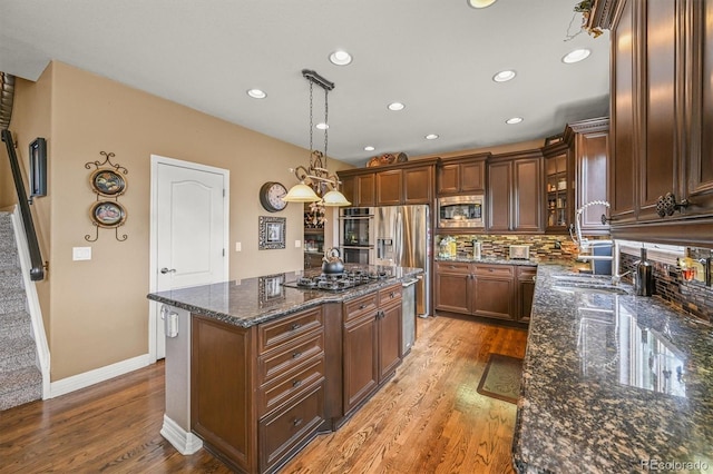 8518 High Rdg, Castle Pines, CO 80108 - kitchen featuring stainless steel appliances, light wood finished floors, a kitchen island, dark stone counters, and backsplash
