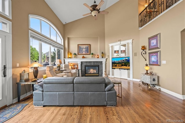 8518 High Rdg, Castle Pines, CO 80108 - living area featuring high vaulted ceiling, wood finished floors, ceiling fan, a glass covered fireplace, and baseboards