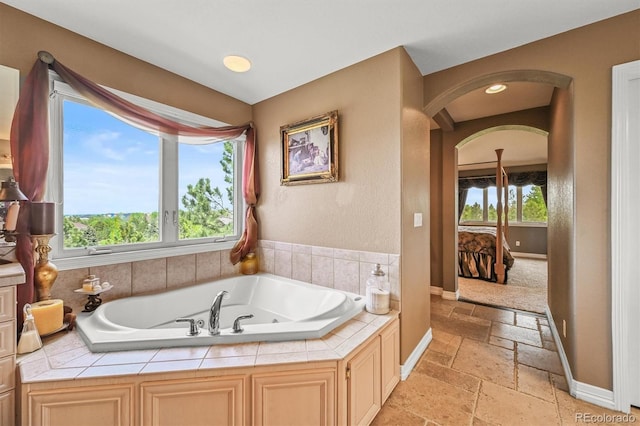 8518 High Rdg, Castle Pines, CO 80108 - ensuite bathroom with stone tile flooring, a garden tub, baseboards, and recessed lighting