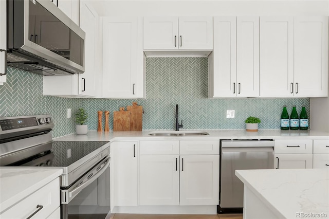 kitchen featuring stainless steel appliances, sink, white cabinets, and backsplash