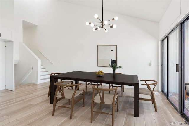 dining room with an inviting chandelier, high vaulted ceiling, and light hardwood / wood-style floors