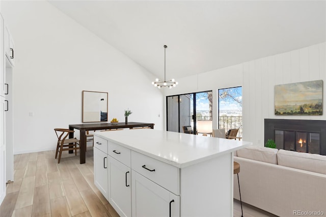 kitchen with hanging light fixtures, a center island, a notable chandelier, white cabinets, and light wood-type flooring