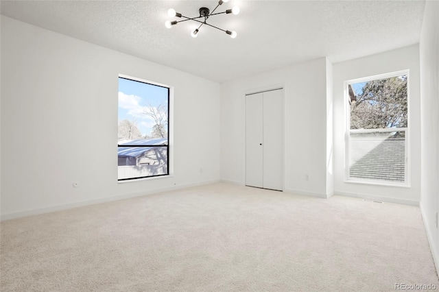 carpeted spare room with a chandelier and a textured ceiling