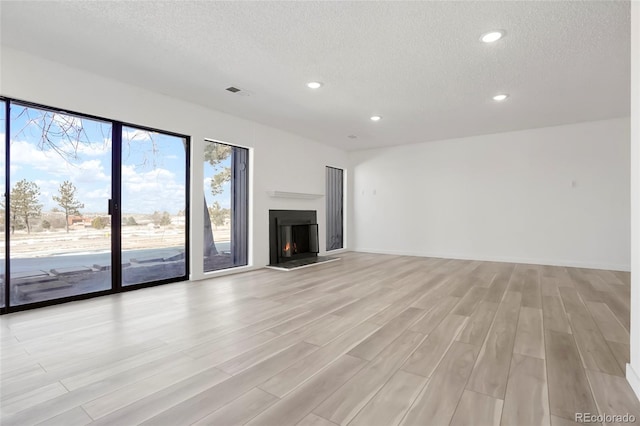 unfurnished living room featuring a textured ceiling and light wood-type flooring