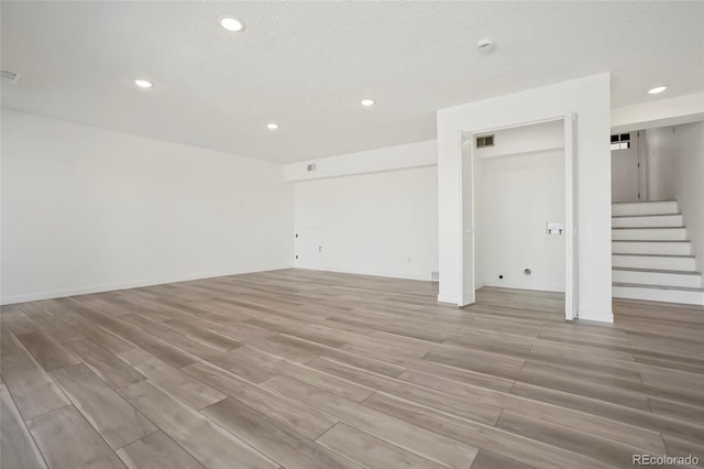 unfurnished room featuring light hardwood / wood-style floors and a textured ceiling