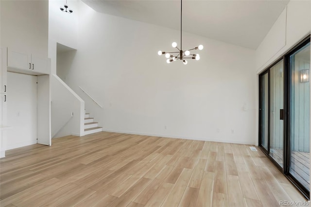 unfurnished living room with a chandelier, high vaulted ceiling, and light wood-type flooring