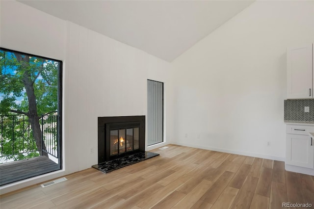 unfurnished living room with high vaulted ceiling and light hardwood / wood-style floors