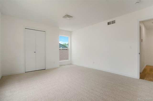 unfurnished bedroom featuring light colored carpet and a closet