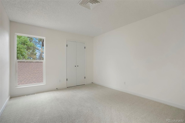 carpeted empty room featuring a textured ceiling