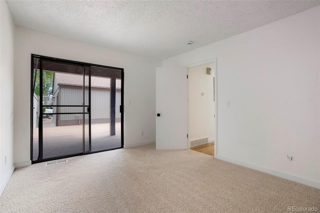 spare room with light carpet and a textured ceiling