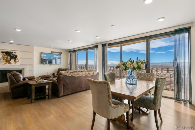 dining area with recessed lighting, a fireplace, a wealth of natural light, and light wood-style floors