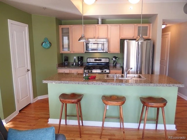 1441 Central St Unit 211, Denver, CO 80211 - kitchen with stainless steel appliances, a sink, a breakfast bar, an island with sink, and light wood-style flooring