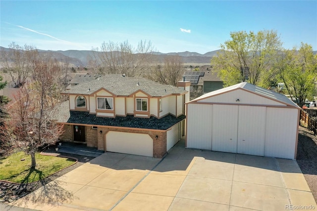 traditional-style home featuring an outbuilding, a mountain view, a garage, and concrete driveway