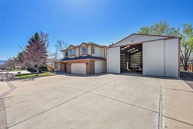 view of front facade featuring an outbuilding, an outdoor structure, brick siding, a garage, and driveway